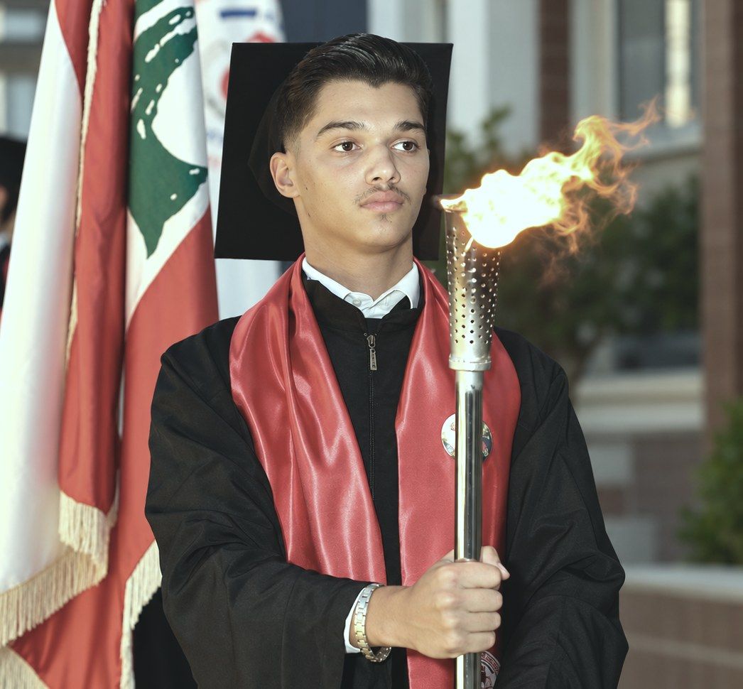 An AMC graduate carrying the torch at graduation